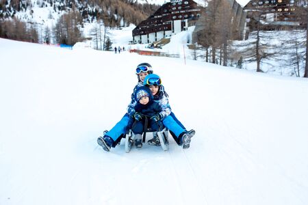 Happy people, children and adults, sliding on a sunny day in Tyrol mountains. Kids having fun while sledgingの写真素材