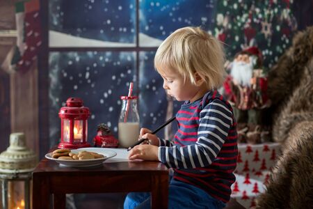 Sweet blonde toddler boy, writing letter to Santa, wishing presents for the holidaysの写真素材