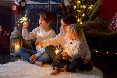 Preschool children, holding sparkler, celebrating new years eve at home