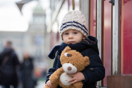 Fashion toddler boy with teddy bear toy in the city center, Christmas timeの写真素材