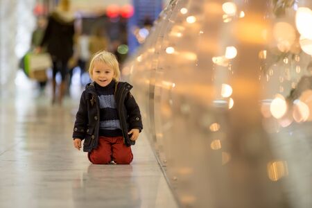 Fashion toddler boy in the city center shopping mall on Christmas time