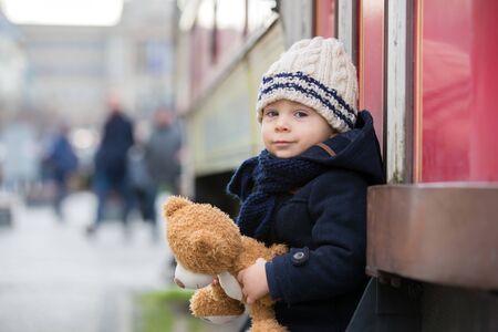 Fashion toddler boy with teddy bear toy in the city center, Christmas timeの写真素材