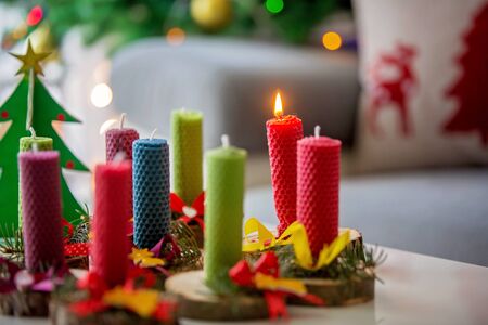 Close shot of natural handmade candles made of beeswax on a wood with christmas decoration on a tableの写真素材