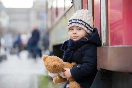 Fashion toddler boy with teddy bear toy in the city center, Christmas timeの写真素材