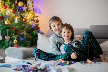 Preschool children, boy brothers, playing together with colorful blocks, building different toys on Christmas day, after opening presents at homeの写真素材