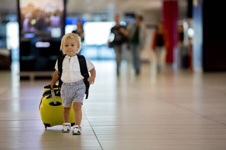 Sweet child, boy, walking at the airport, carrying suitcase and backpack, family holidayの写真素材