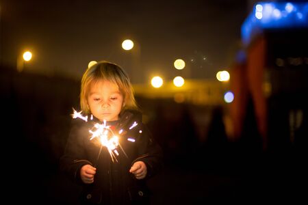 Waist up portrait of happy children celebrating New Year together and lighting sparklers outdoors in gardenの写真素材