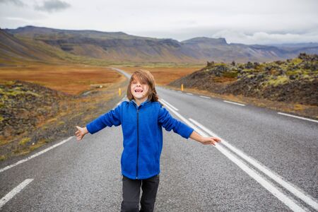 Kid running on an empty road in beautiful nature in Snaefellsjokull National Park in Iceland, autumntime on sunsetの写真素材