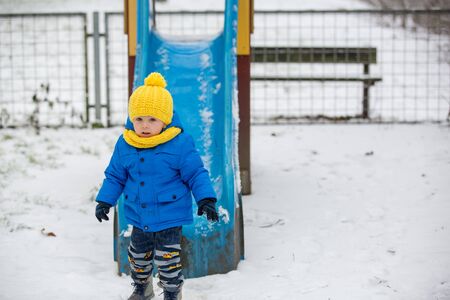Sweet toddler boy, playing with snow on playground, kid play with snowの写真素材