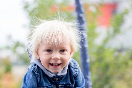 Cute little boy with static electricy hair, having his funny portrait taken outdoors on a trampolineの写真素材