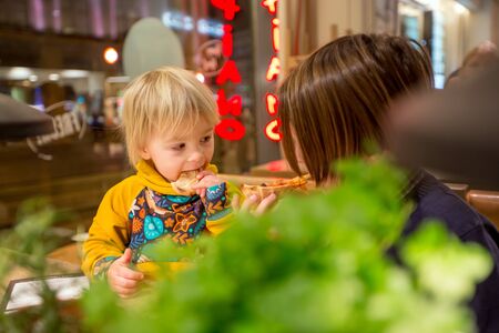 Happy european children, eating pizza at a restaurant, evening timeの写真素材