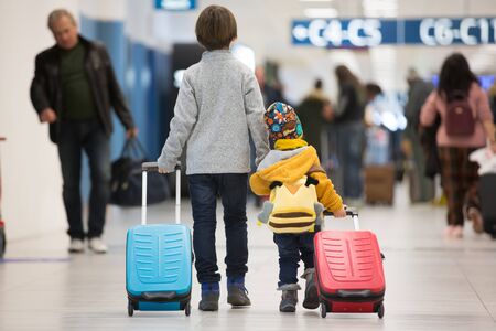 Blonde toddler boy with family, traveling with airplane, running at the airport with suitcaseの写真素材