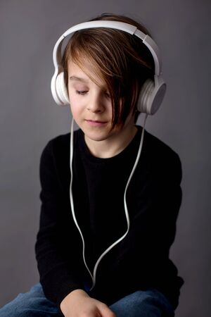 Sweet child, boy in black sweater, listening music, isolated backgroundの写真素材