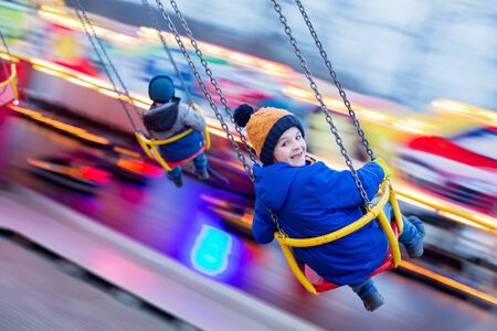 Child, cute boy riding chain swing carousel on sunset, motion blur, colorful backgroundの写真素材