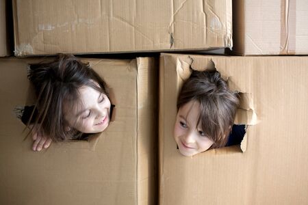 Sweet children,  boy brothers, hiding in cardboard box, looking out, isolated, sad kids, staying at home, due to  quarantineの写真素材