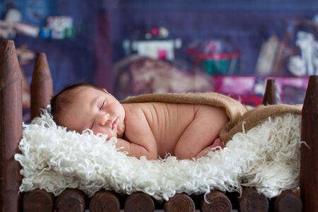Little newborn baby boy, sleeping in wooden baby bed with little chick, sweet animal friendの写真素材