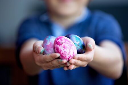 Sweet children, brothers, coloring and paiting eggs for Easter in garden, outdoors at home in...