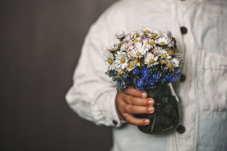 Toddler child, holding old vintage keys and bouquet of wild flowers in little vaseの写真素材
