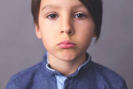 Child, boy, showing different emotions, isoalted shot on gray backgroundの写真素材