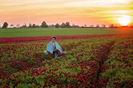 Beautiful children, brothers in gorgeous crimson clover field on sunset, springtimeの写真素材
