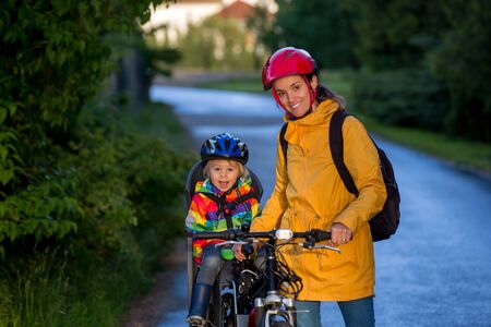 Mother and child, riding bike, boy sitting in bike seat, enjoying trip with mom, safety first, waearing helmetsの写真素材