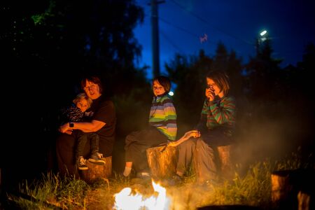 Happy kids roasting sausages on campfire at eveningの写真素材