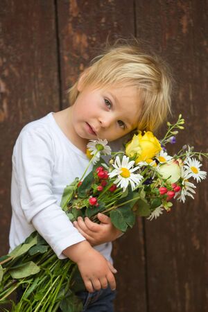 Blond toddler boy, hodling bouquet of flowers, close portraitの写真素材