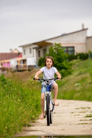 Child, boy, riding bike in muddy puddle, summer time on a rainy dayの写真素材