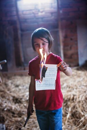 Preteen child, burning paper in the attic, seting it on fireの写真素材
