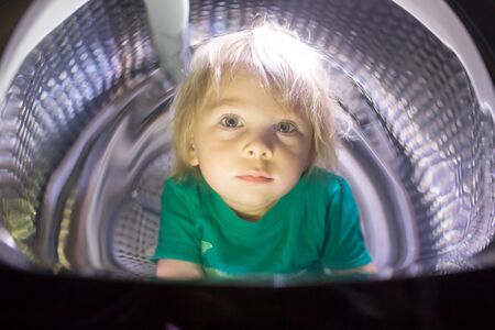 Happy child, sitting in thumble dryer, smiling happily