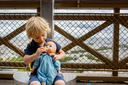 Cute toddler boy, playing with doll on the Eiffel tower, visiting Parisの写真素材