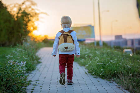 Cute blond preschool child, wearing medical mask dressed in uniform, going to preschool for the...