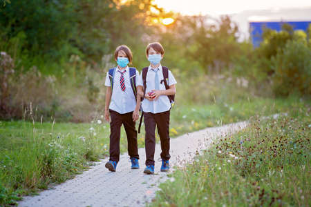 School children, boys wearing medical masks, going back to school after the summer vacation, kids...