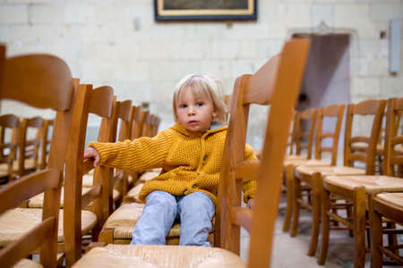 Little toddler boy, praying in chapel with candles in front of himの写真素材