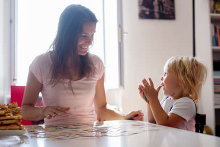 Mother, teaching her child toddler boy the alphabet and numbers, educating him