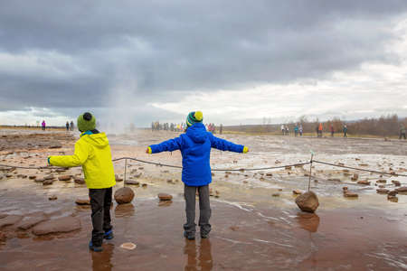 Children, enjoying the eruption of Strokkur Geysir in Iceland autumntimeの写真素材