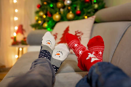 Four pair of feet in Christmas socks, mom and children lying on the couch, enjoying christmas time togetherの写真素材