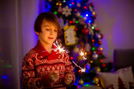 Waist up portrait of happy child celebrating New Year together and lighting sparklers at home