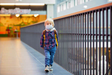 Toddler child, boy, wearing protective medical mask in shopping center during coronavirus Covid 19 pandemicの写真素材