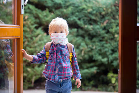 Child, putting medical protective mask before entering kindergarten in the morningの写真素材