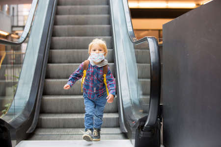 Toddler child, boy, wearing protective medical mask in shopping center during coronavirus Covid 19 pandemicの写真素材