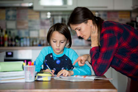 Mother, helping her child with homeworks, kid learning at home during pandemic Covid 19 lockdown