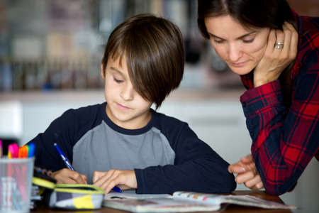 Mother, helping her child with homeworks, kid learning at home during pandemic Covid 19 lockdownの写真素材