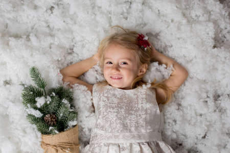 Cute blond child baby girl, playing in the snow on a winter snowy dayの写真素材