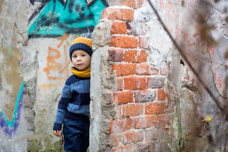 Child, posing in an old ruin building, sprayed with graffiti drawingsの写真素材