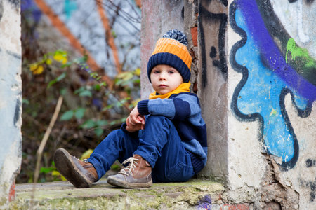 Child, posing in an old ruin building, sprayed with graffiti drawingsの写真素材