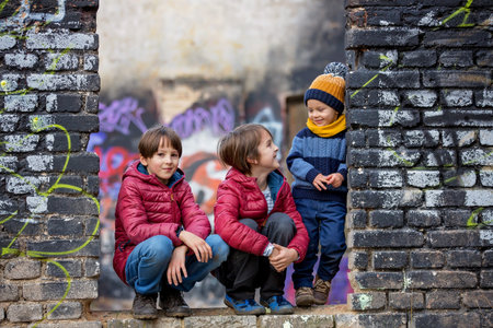 Children, siblings, posing in an old ruin building, sprayed with graffiti drawingsの写真素材