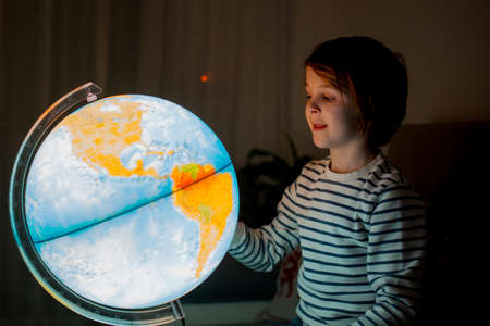 Little child, looking at illuminated globe, exploring the world, learningの写真素材