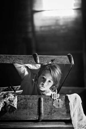 Little child, boy, hiding in old vintage suitcase in the attic, scared not to be found