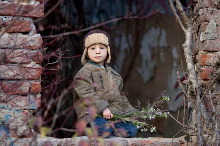 Cute child, posing in a ruin brick house, sitting on a window shield, autumn timeの写真素材